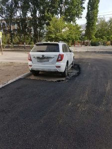 В Астрахани рабочие положили асфальт вокруг припаркованного авто