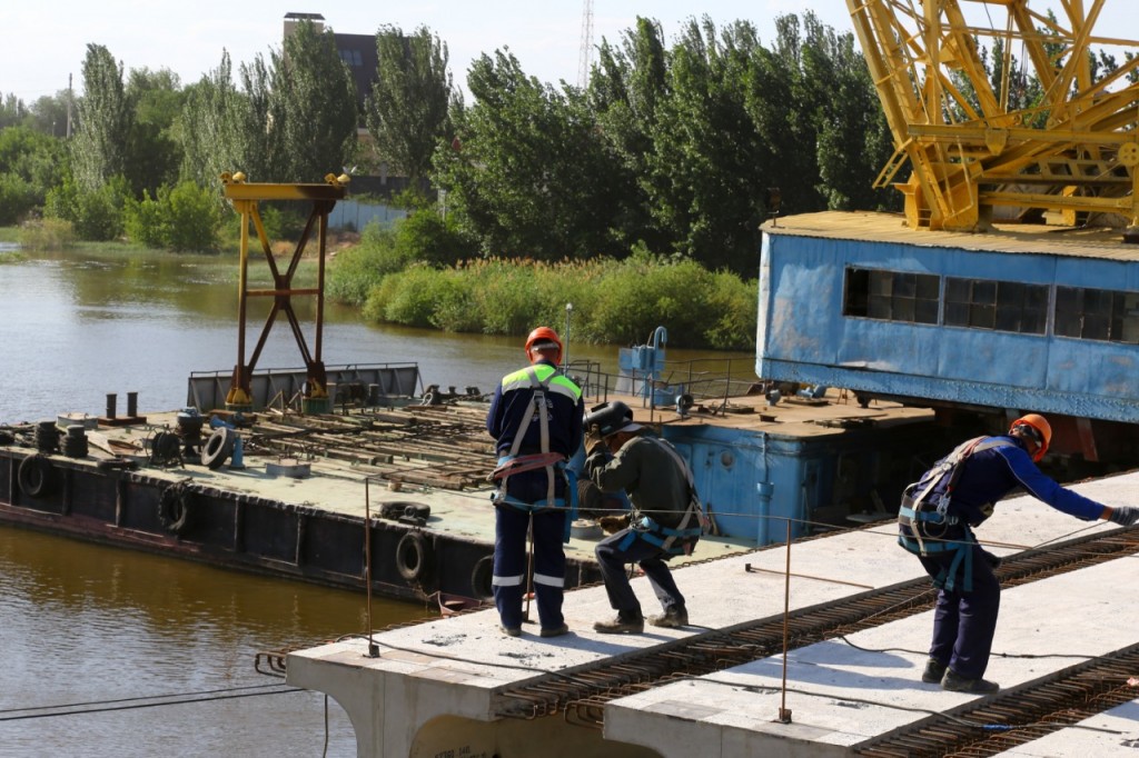 Дома строятся или строются. Плавучие опоры моста. Строить мост через реку. Мост Царев Астрахань. Плавучий мост на сваях.